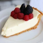 A slice of keto cheesecake recipe no bake topped with fresh raspberries and blackberries on a white plate.