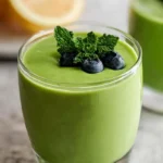 A creamy glass of the best keto green smoothie recipe, topped with fresh blueberries and mint leaves, perfect for a refreshing low-carb treat.