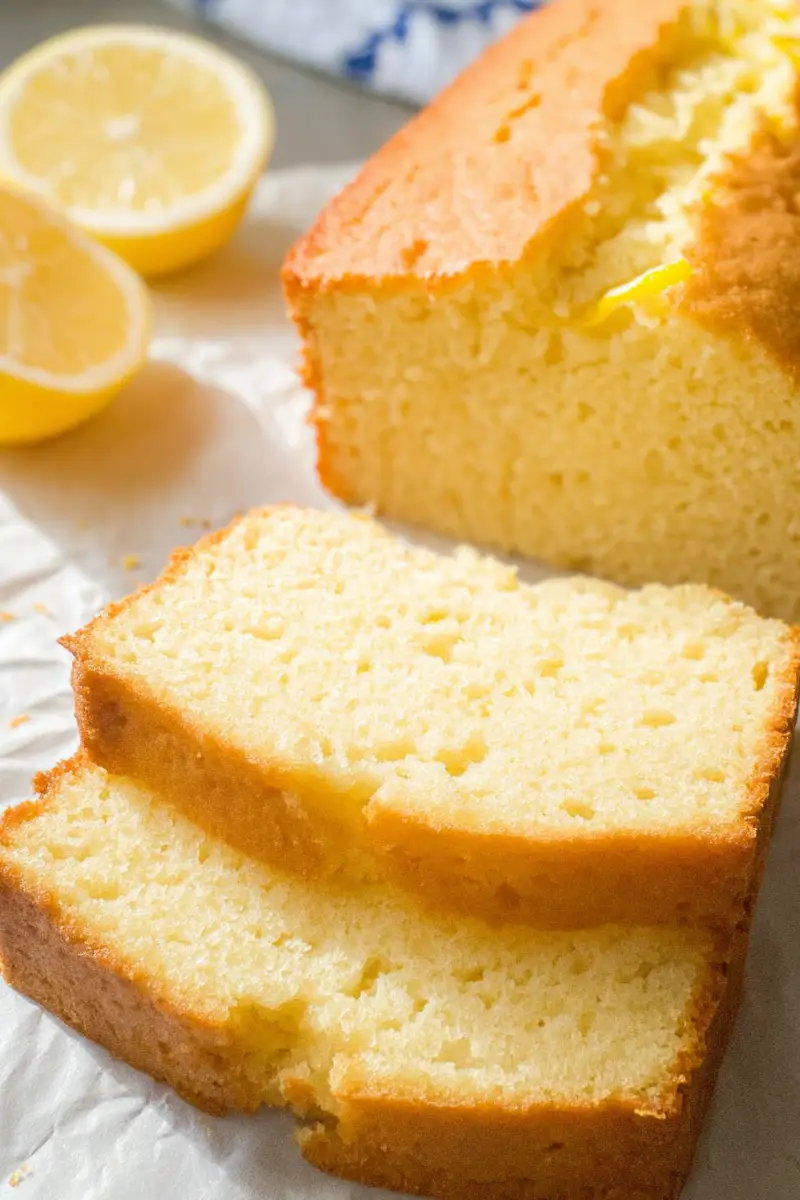 Slice of moist and fluffy cake from a Keto Lemon Cake Recipe, displayed on parchment paper with a golden crust and zesty lemon aroma.