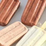 Four creamy keto ice cream bars in chocolate, vanilla, and light mocha flavors arranged on a white plate.