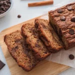 Sliced keto chocolate banana bread recipe on a wooden cutting board with chocolate chips.
