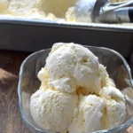 Keto vanilla ice cream recipe scoops in a glass bowl with creamy low carb ice cream in a pan behind