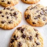 Keto Chocolate Chip Cookies fresh out of the oven on a baking sheet lined with parchment paper