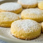 Keto lemon cookies arranged on a plate with a light golden crust, dusted lightly with powdered sweetener, showing a soft, tender texture perfect for low-carb lemon desserts.